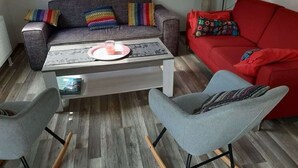 A living room with a grey sofa, a red sofa, a coffee table, and two grey chairs. - Holiday Home in Quiet Environment near Beach & Dunes (Groet)