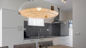 A modern kitchen with white cabinets, a grey countertop, and a wooden dining table with two salt shakers. - Bungalow at Nieuwvliet Bad Beach Resort (Nieuwvliet)