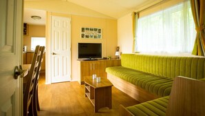 A cozy living room with a green sofa, wooden coffee table, and a flat-screen TV on a wooden cabinet. - Apartment in Utrecht Near Historic Windmill (Udenhout)