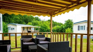 A covered outdoor area with wicker furniture and a wooden deck. - Apartment in Utrecht Near Historic Windmill (Udenhout)