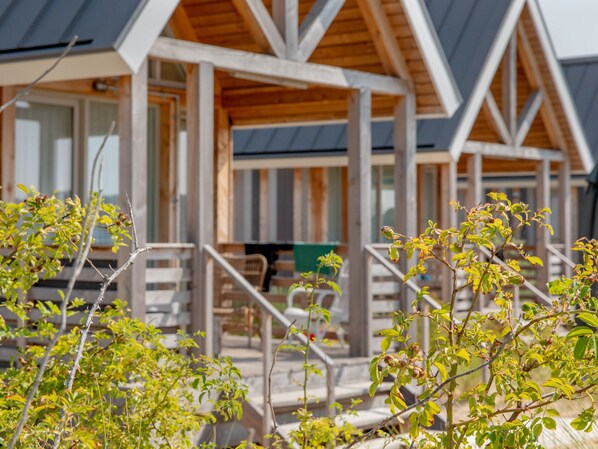 A wooden cabin with a porch and outdoor seating area.