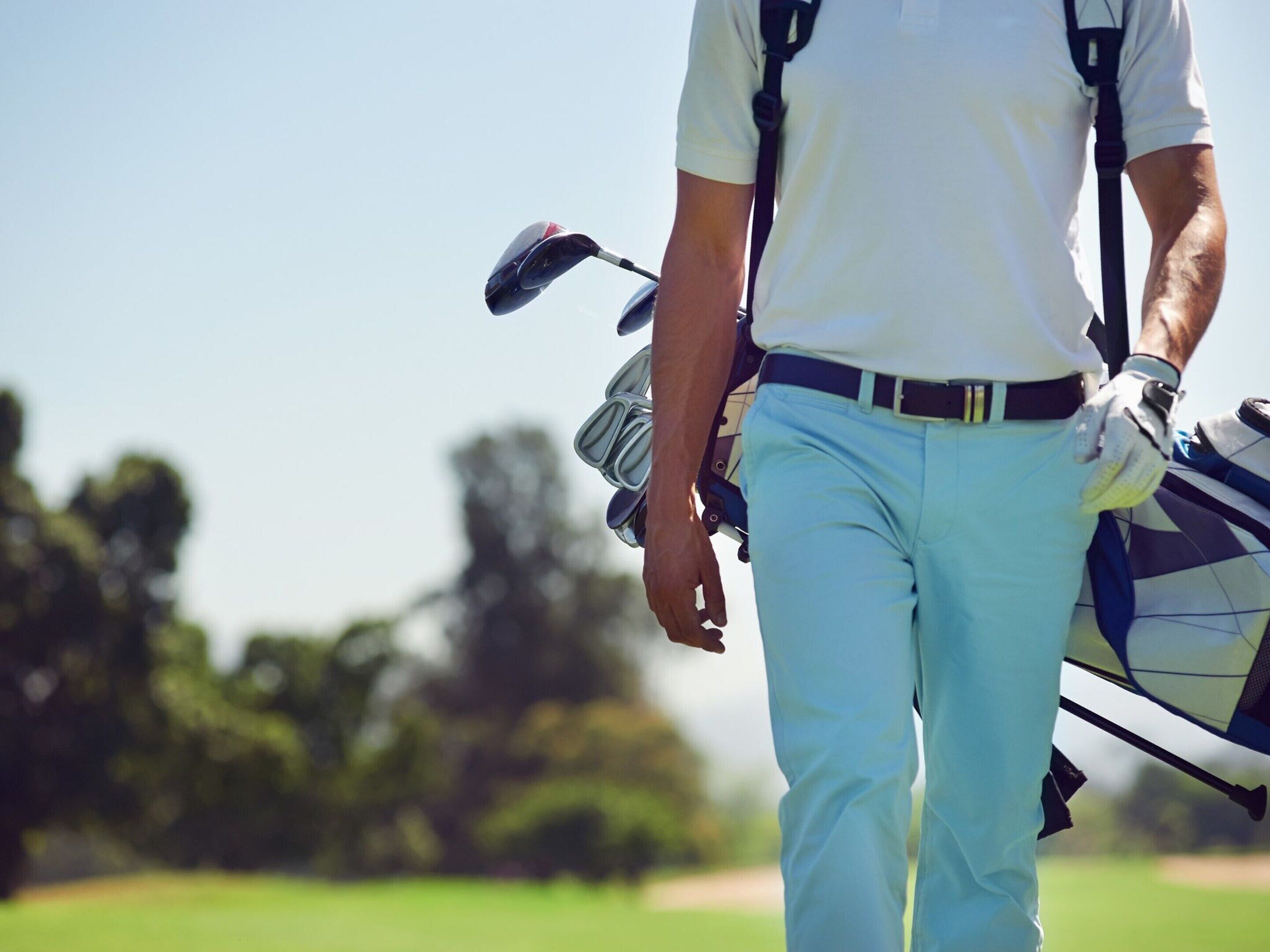A person carrying a golf bag, walking on a golf course.