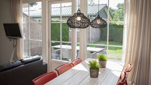A dining area with a white table, red chairs, and two potted plants. - Detached Combined Bungalow with Garden near Veluwe (Voorthuizen)