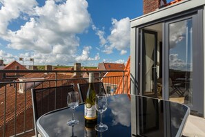 A balcony with a table, a bottle of wine, and two glasses.