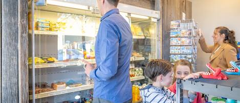 A refrigerated display case with various food items and a person pointing at it.