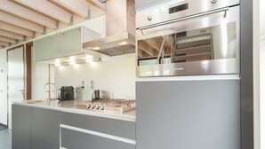 Eine moderne Küche mit Edelstahlgeräten, einem eingebauten Backofen und einer großen Kochinsel mit Spüle und Arbeitsplatte.