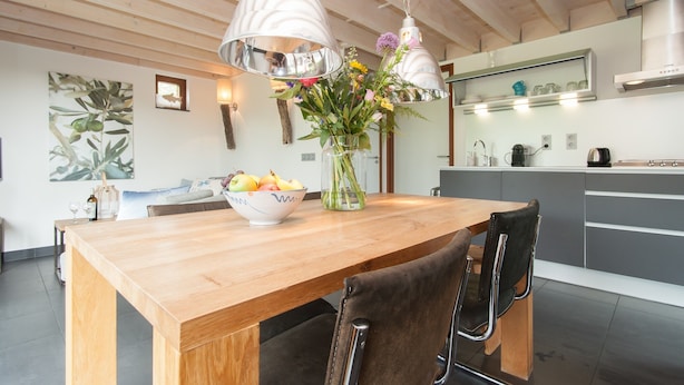 Eine moderne Küche mit einem Holzesstisch, einer Vase mit Blumen und einer Obstschale.