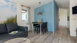 Un salon moderne avec un canapé en cuir noir, une table basse ronde et un coin repas comprenant une table et des chaises.