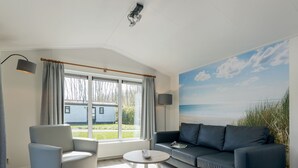 Un salon moderne avec une grande fenêtre, un canapé, un fauteuil et une table basse.