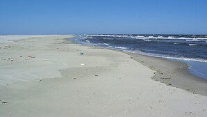 Ein Strand mit klarem Himmel und ruhigem Meer.