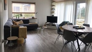 Ein modernes Wohnzimmer mit einer Couch, einem runden Esstisch und einem Fernseher.