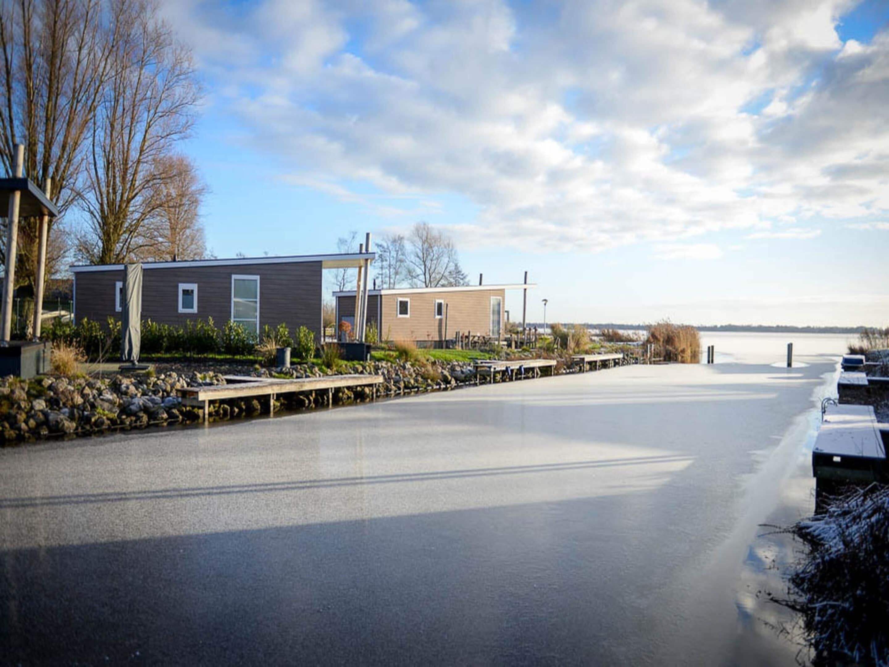 A waterfront property with modern cabins, a paved walkway, and a view of the water.