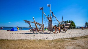 A beach with a large wooden pirate ship structure, a blue tent, and people engaging in activities. - Detached Bungalow With a Dishwasher Near Leeuwarden (Sumar)