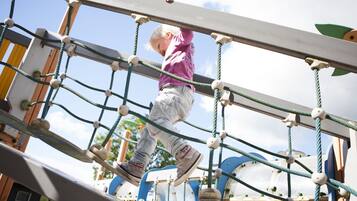 Un bambino sale su un ponte di corda in un parco giochi.
