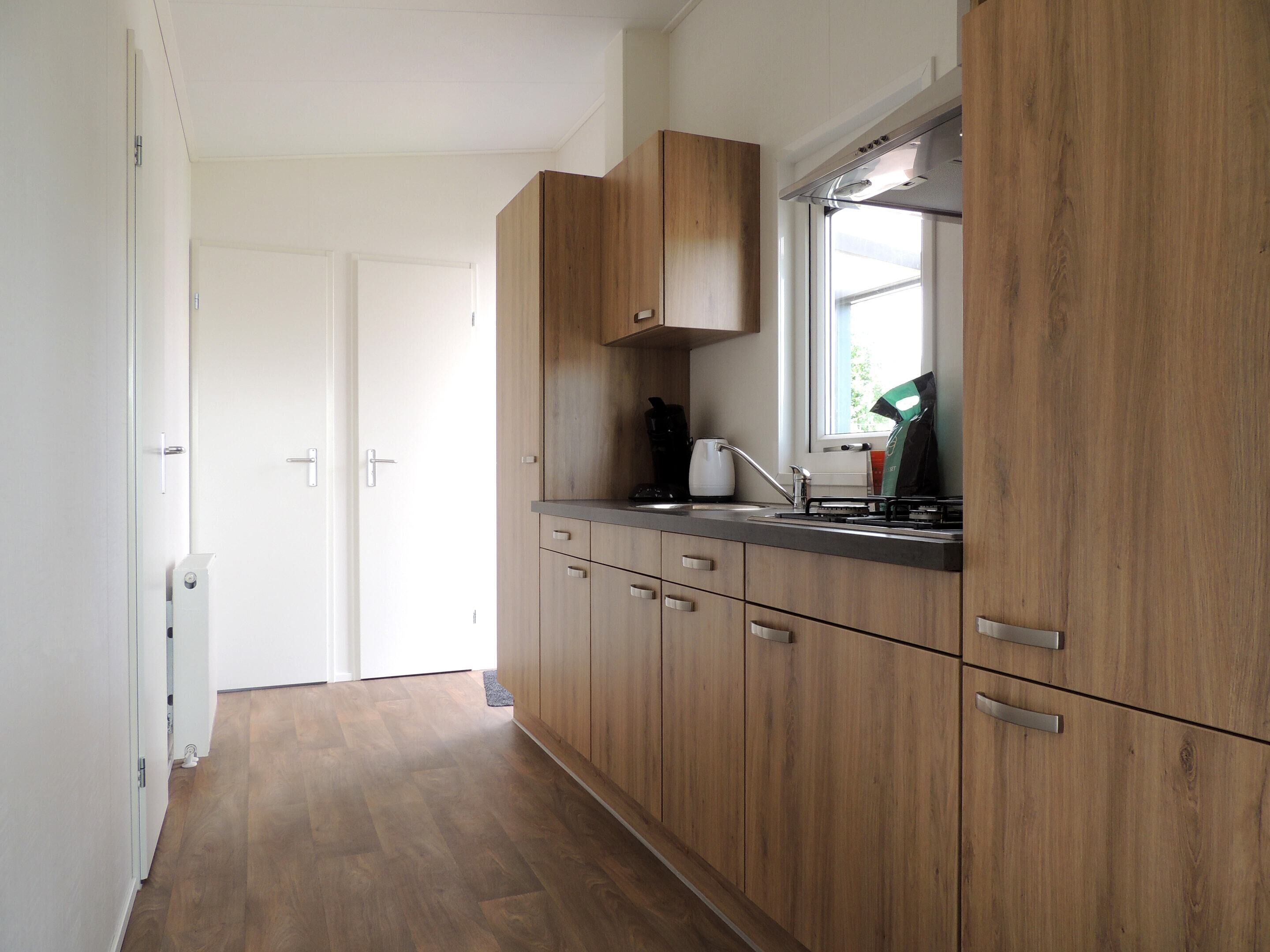A kitchen with wooden cabinets, a stainless steel sink, and a window above the counter.