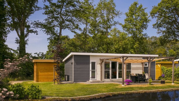 Una casa moderna con un porche cubierto, un jardín pequeño y un estanque.
