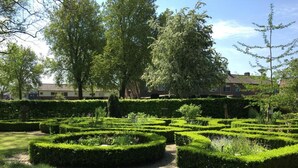 Un jardín formal con setos geométricos y un sendero.
