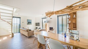 Cozinha moderna com mesa de jantar de madeira, cadeiras brancas e detalhe no teto em madeira.