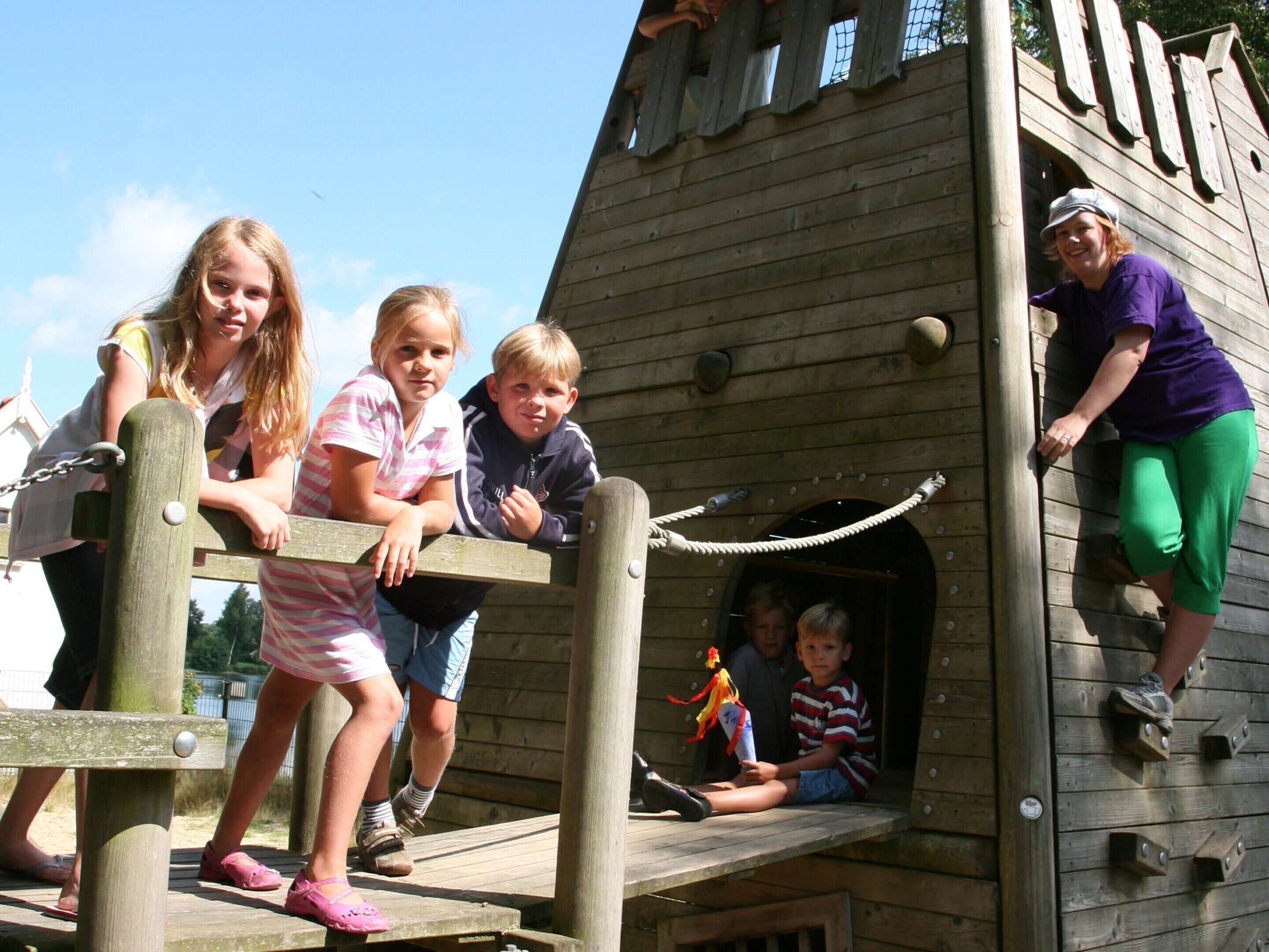 A wooden play structure with climbing elements and a rope for safety.
