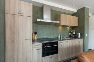 A modern kitchen with wooden cabinets, a stainless steel range hood, and a built-in oven.