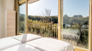 Une chambre avec une grande fenêtre, un lit et une armoire.