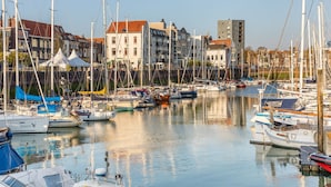 Un port de plaisance où sont amarrés de nombreux bateaux, entouré de bâtiments présentant différents styles architecturaux.