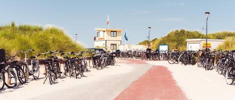 A bicycle parking area with a red pathway leading to a building with flags.