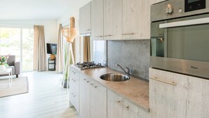 Una cocina moderna con armarios de madera clara, electrodomésticos de acero inoxidable y un ventanal que proporciona luz natural.