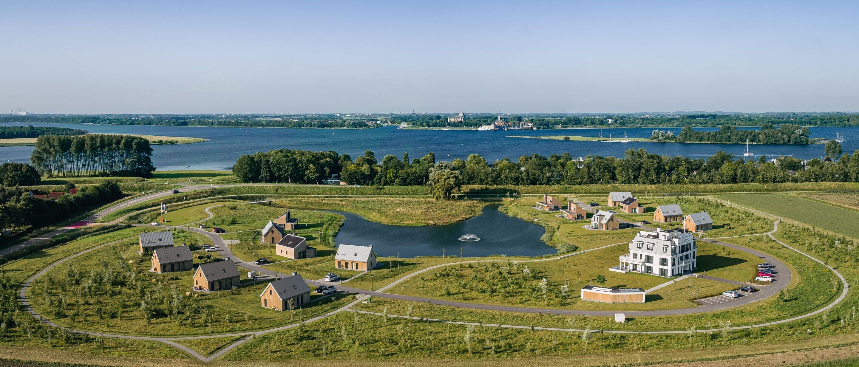 An aerial view of a residential area with houses, a large lake, and a distant cityscape.