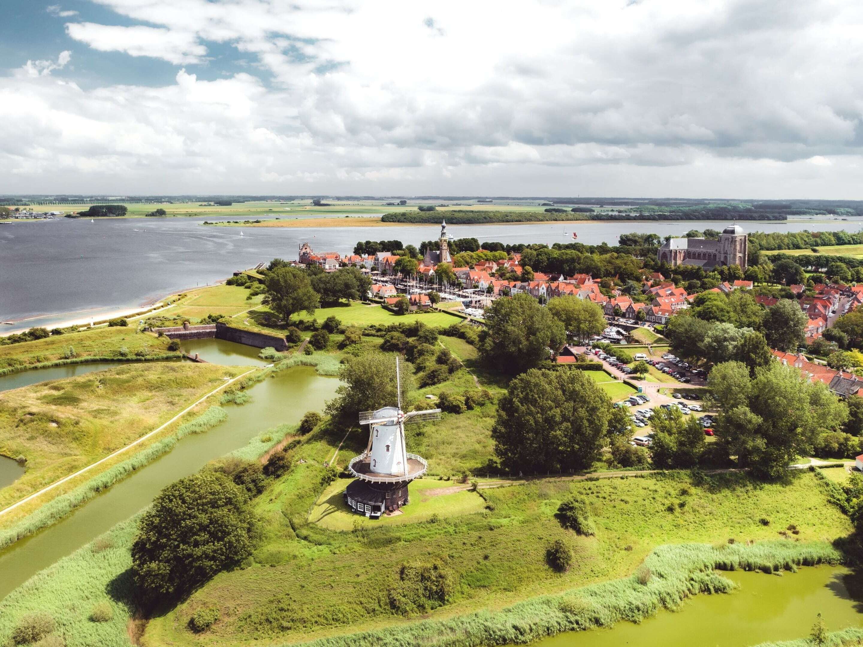 A coastal town with a prominent windmill, historic buildings, and a river.