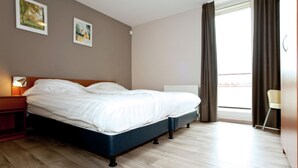 A bedroom with a bed, a nightstand, a window with curtains, and two wall-mounted pictures. - Villa With Lake Views (Heel)