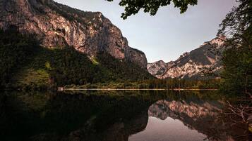 Un lago de montaña con reflejos de los riscos y árboles circundantes.