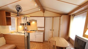Een kleine keuken in een camper met een eethoek, een televisie en een ventilator.