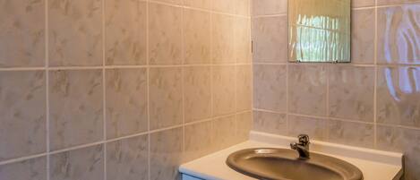 A bathroom with a sink, mirror, and tiled walls.