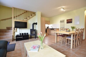 A living room with a sofa, a coffee table with a book and a vase of flowers, a TV, a fireplace, and a staircase.