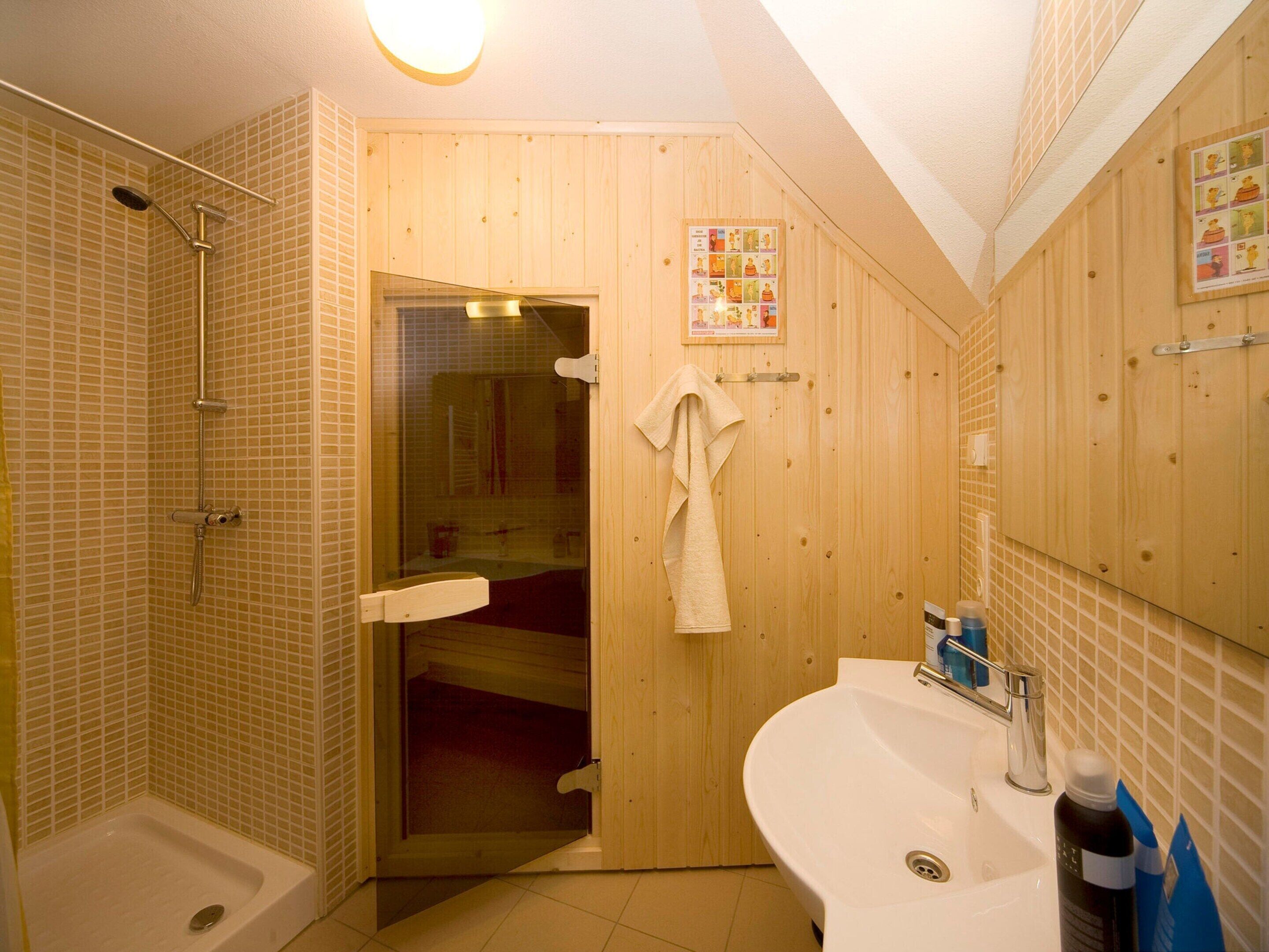 Une salle de bain avec une douche, un lavabo et une porte en bois.
