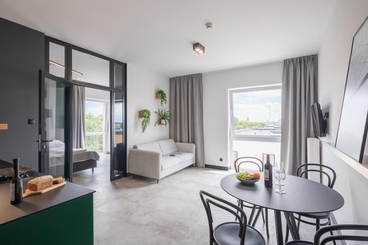 Una habitación de hotel moderna con comedor, sofá y vista a la ciudad.