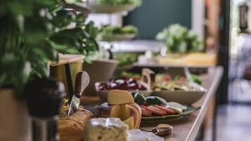 Una mesa de buffet con diversos alimentos, entre ellos queso, pan y verduras.