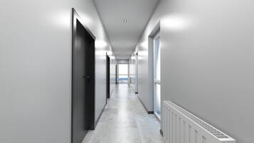 A long, narrow hallway with a tiled floor, white walls, and a radiator on the right.
