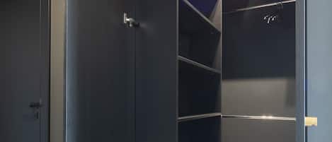 Un armario moderno con puertas de madera oscura, estantes empotrados y una lámpara arriba.