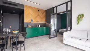 Una cocina moderna con encimera verde, un comedor con mesa y sillas blancas, y un sofá blanco.