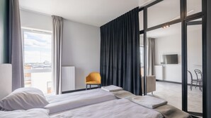 Una habitación de hotel con cama, una silla, un televisor y vistas a la ciudad.