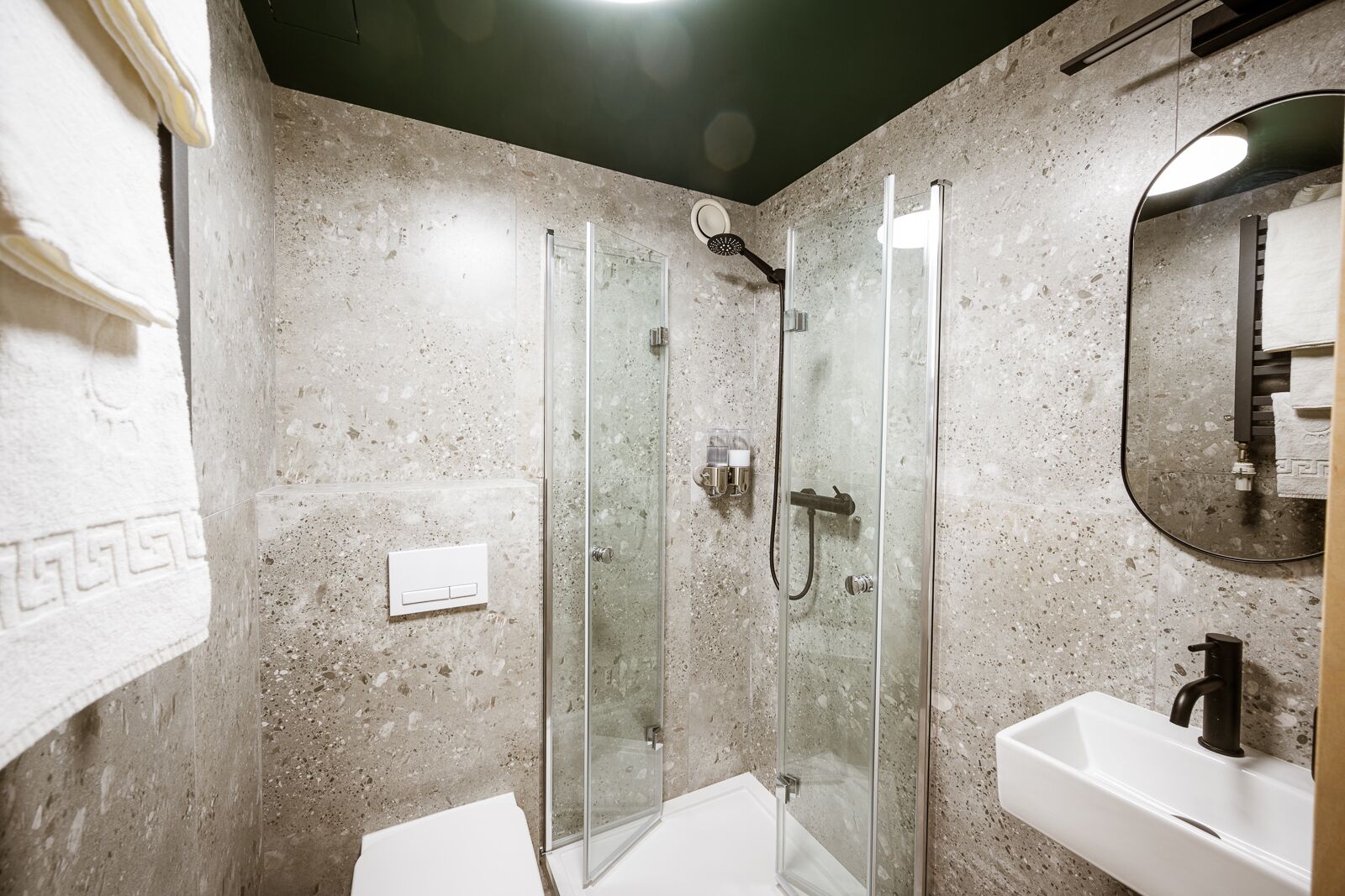 A bathroom with a glass-enclosed shower, a white sink, and a mirror.