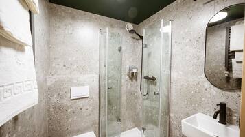 Ein Badezimmer mit einer Duschkabine, einem weißen Waschbecken und einem Spiegel.