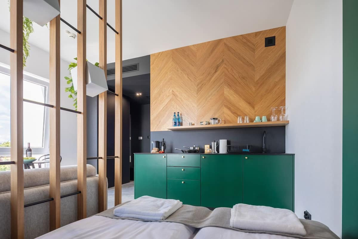 Un dormitorio moderno con una cama, un aparador verde y un panel de pared de madera.