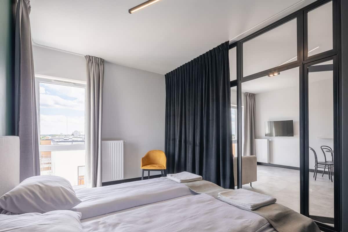 Una habitación de hotel con cama, una silla, un televisor y vistas a la ciudad.