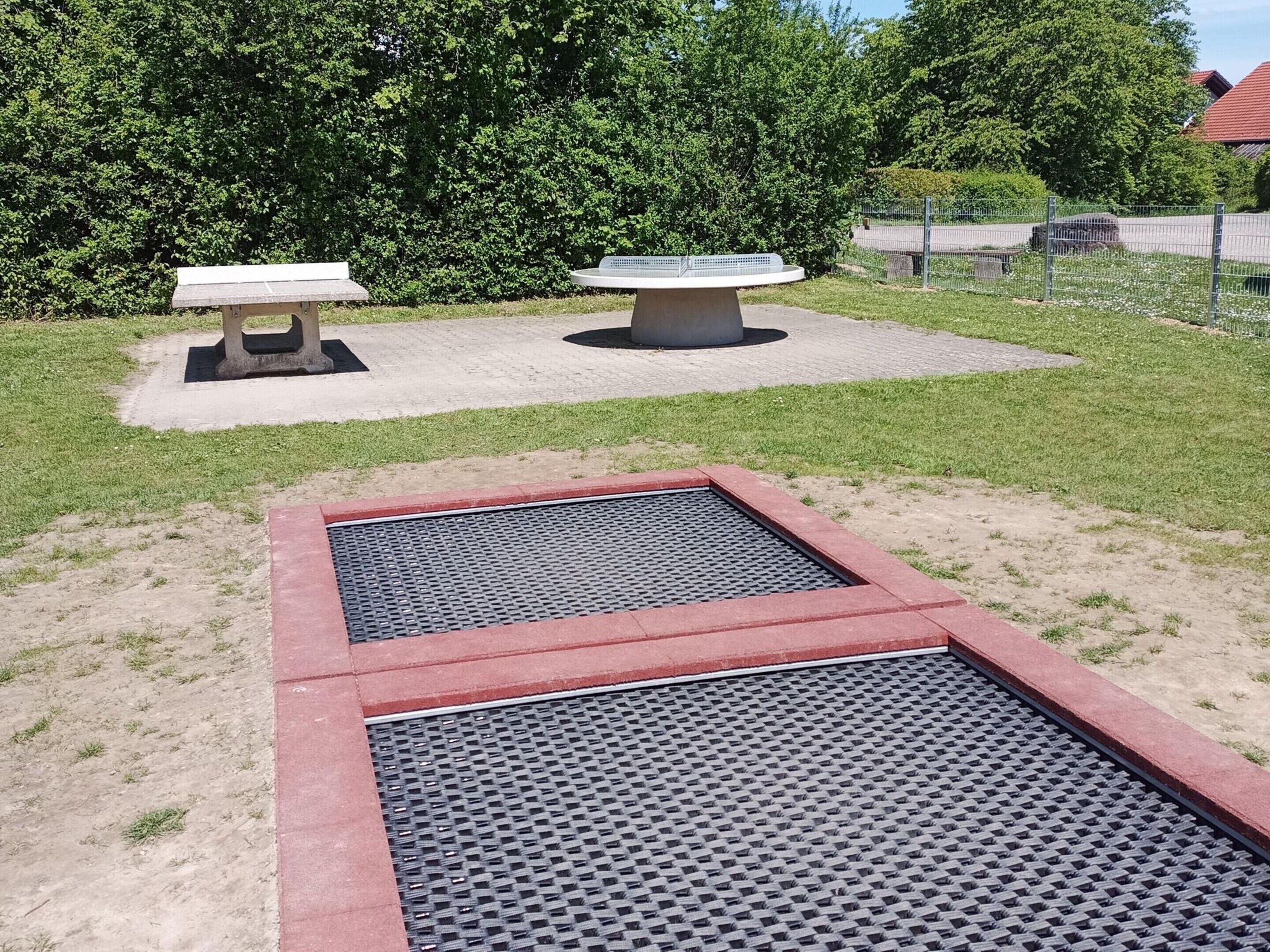 A park with a concrete bench and a circular information plaque.