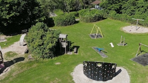 Eine Luftaufnahme eines Parks mit Spielgeräten, einer Holzkonstruktion und einem gepflasterten Weg.