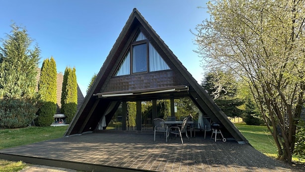 Ein modernes, dreieckiges Haus mit überdachter Terrasse.