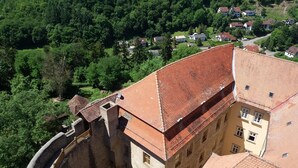Ein historisches Gebäude mit rotem Ziegeldach, Steinmauer und Innenhof.
